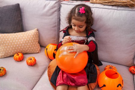 Téléchargez les photos : Adorable fille hispanique portant un costume d'Halloween dessin sur ballon à la maison - en image libre de droit