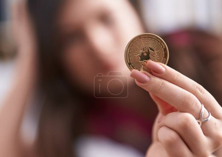 Foto de Joven mujer caucásica sosteniendo moneda uniswap en casa - Imagen libre de derechos