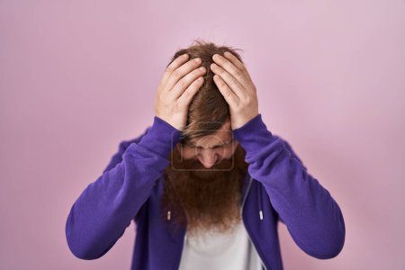 Photo for Caucasian man with long beard standing over pink background suffering from headache desperate and stressed because pain and migraine. hands on head. - Royalty Free Image