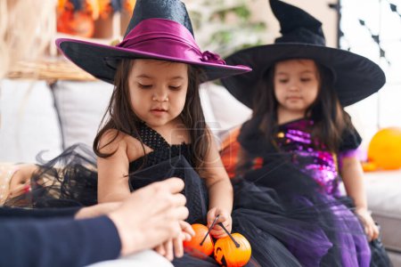 Téléchargez les photos : Adorable jumelles ayant fête d'Halloween dessin sur la main à la maison - en image libre de droit