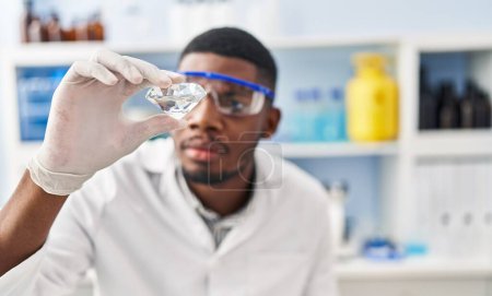 Photo for Young african american man wearing scientist uniform holding diamond at laboratory - Royalty Free Image