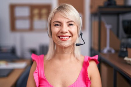 Foto de Joven mujer caucásica usando auriculares de agente de call center que se ven positivos y felices de pie y sonriendo con una sonrisa confiada mostrando los dientes - Imagen libre de derechos