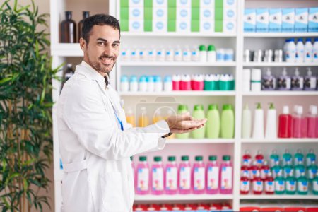 Photo for Handsome hispanic man working at pharmacy drugstore pointing aside with hands open palms showing copy space, presenting advertisement smiling excited happy - Royalty Free Image