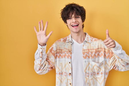 Téléchargez les photos : Jeune homme portant une chemise d'été décontractée montrant et pointant vers le haut avec les doigts numéro six tout en souriant confiant et heureux. - en image libre de droit