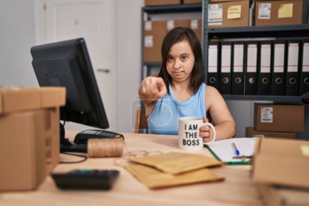 Photo for Hispanic girl with down syndrome working at small business ecommerce pointing with finger to the camera and to you, confident gesture looking serious - Royalty Free Image