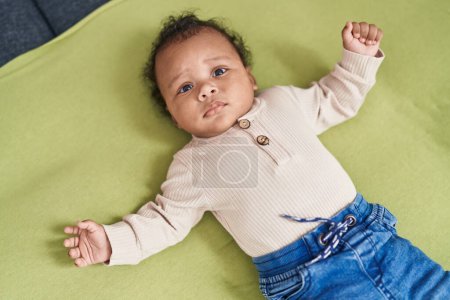 Téléchargez les photos : Bébé afro-américain se relaxant au lit dans la chambre - en image libre de droit