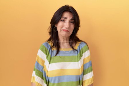 Photo for Middle age hispanic woman standing over yellow background depressed and worry for distress, crying angry and afraid. sad expression. - Royalty Free Image