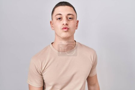 Photo for Young man standing over isolated background looking at the camera blowing a kiss on air being lovely and sexy. love expression. - Royalty Free Image