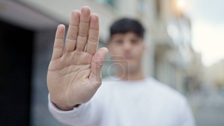 Photo for Young hispanic man doing stop gesture with hand at street - Royalty Free Image