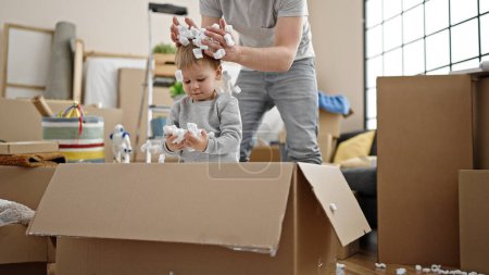 Téléchargez les photos : Père et fils jouant avec la boîte en carton de mousse à la nouvelle maison - en image libre de droit