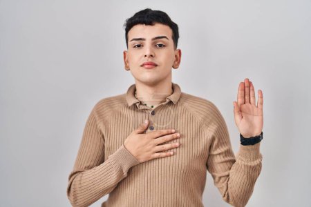 Photo for Non binary person standing over isolated background swearing with hand on chest and open palm, making a loyalty promise oath - Royalty Free Image