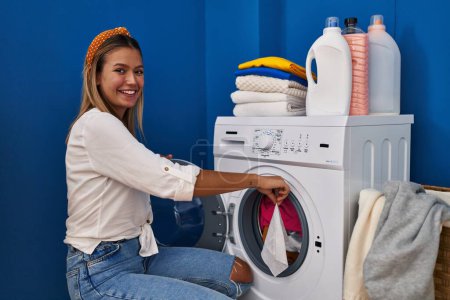 Foto de Young hispanic woman smiling confident washing clothes at laundry room - Imagen libre de derechos