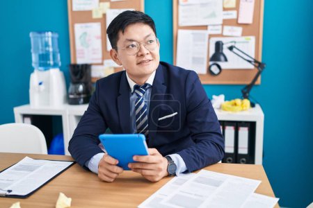 Foto de Joven hombre chino trabajador de negocios utilizando touchpad en la oficina - Imagen libre de derechos