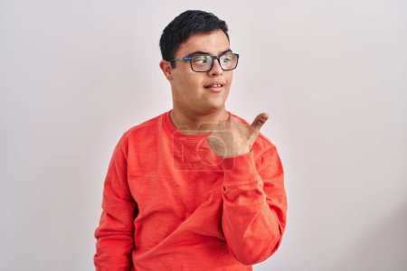 Photo for Young hispanic man with down syndrome standing over white background pointing thumb up to the side smiling happy with open mouth - Royalty Free Image