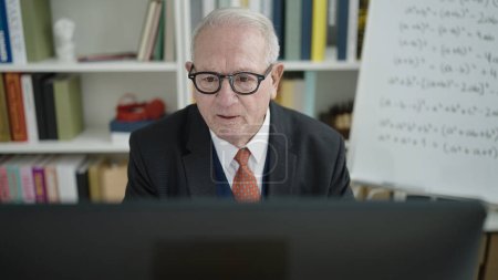 Téléchargez les photos : Professeur d'université senior utilisant l'ordinateur à la salle de classe universitaire - en image libre de droit