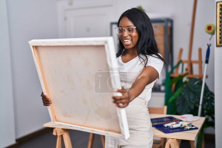 Téléchargez les photos : Jeune artiste afro-américaine souriante regardant le dessin au studio d'art - en image libre de droit