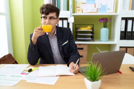 Téléchargez les photos : Non binary man business worker writing on document drinking coffee at office - en image libre de droit