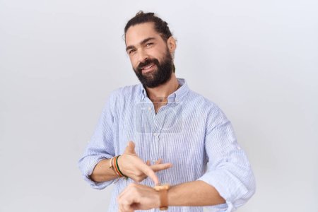 Téléchargez les photos : Homme hispanique avec barbe portant chemise décontractée à la hâte pointant pour regarder le temps, l'impatience, bouleversé et en colère pour retard de délai - en image libre de droit
