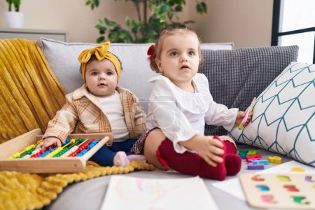 Téléchargez les photos : Adorables filles jouer avec abaque tenant des ciseaux à la maison - en image libre de droit