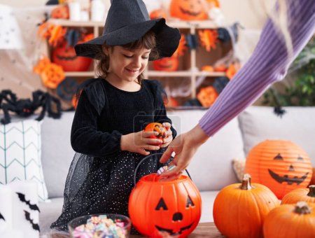 Photo for Adorable hispanic girl having halloween party receiving sweets at home - Royalty Free Image