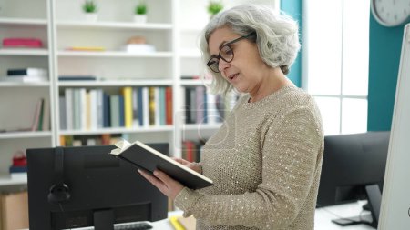 Foto de Mujer de mediana edad con profesor de pelo gris leyendo libro en el aula universitaria - Imagen libre de derechos