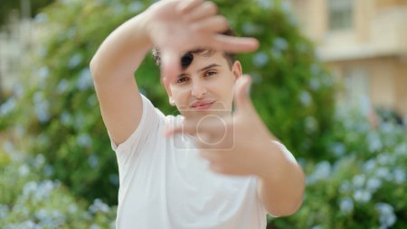 Téléchargez les photos : Non binary man smiling confident doing photo gesture with hands at park - en image libre de droit