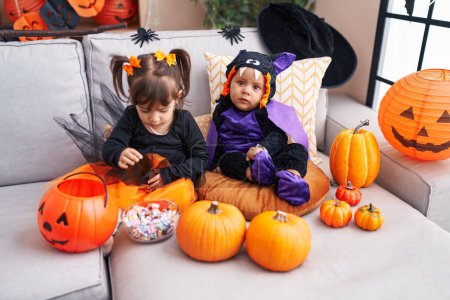 Téléchargez les photos : Adorable garçon et fille ayant fête d'Halloween tenant des bonbons à la maison - en image libre de droit