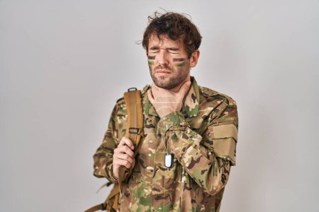 Foto de Joven hispano vistiendo uniforme camuflaje del ejército tocando doloroso cuello, dolor de garganta por gripe, clod e infección - Imagen libre de derechos