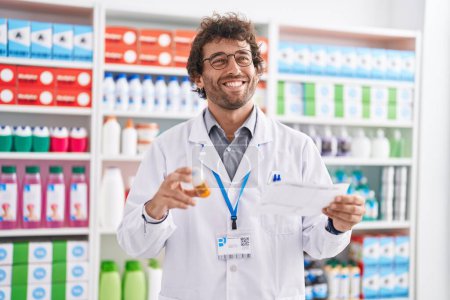 Photo for Young hispanic man pharmacist holding pills bottle reading prescription at pharmacy - Royalty Free Image