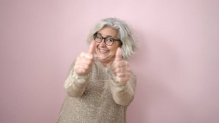 Photo for Middle age woman with grey hair smiling with thumbs up over isolated pink background - Royalty Free Image