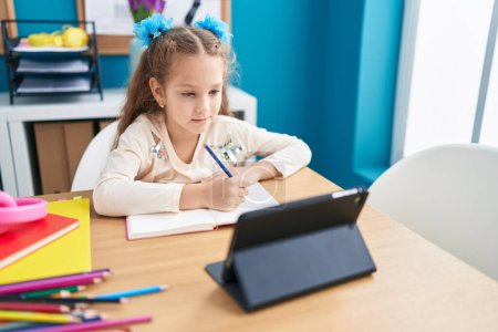 Photo for Adorable caucasian girl student using touchpad writing on notebook at office - Royalty Free Image