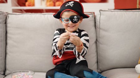 Foto de Adorable niño hispano con traje de pirata sosteniendo dulce en casa - Imagen libre de derechos