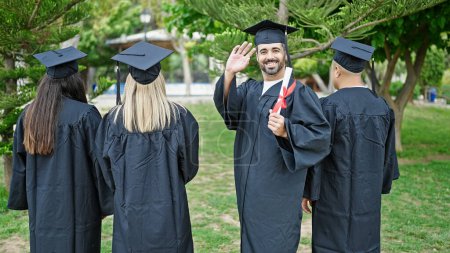 Photo for Group of people students graduated holding diploma saying hello with hand at university campus - Royalty Free Image