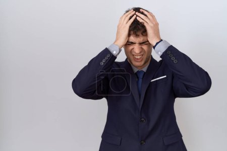 Photo for Young hispanic business man wearing suit and tie suffering from headache desperate and stressed because pain and migraine. hands on head. - Royalty Free Image