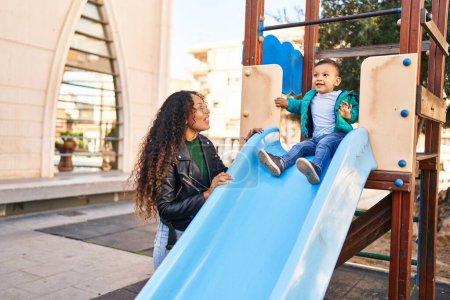 Téléchargez les photos : Mother and son playing on slide at park - en image libre de droit
