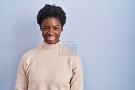 Téléchargez les photos : Femme afro-américaine debout sur fond bleu avec un sourire heureux et cool sur le visage. chanceux. - en image libre de droit
