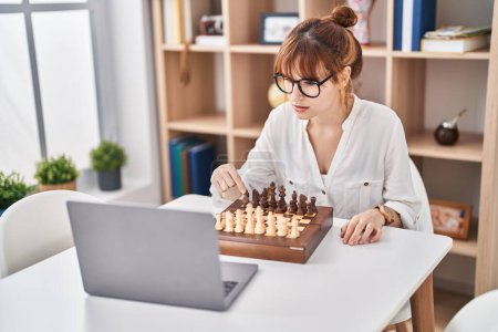 Téléchargez les photos : Jeune femme jouant jeu d'échecs en ligne à la maison - en image libre de droit