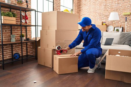 Photo for Young hispanic man worker packing package at new home - Royalty Free Image
