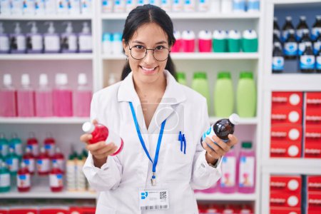 Photo for Young beautiful hispanic woman pharmacist smiling confident holding medication bottles at pharmacy - Royalty Free Image