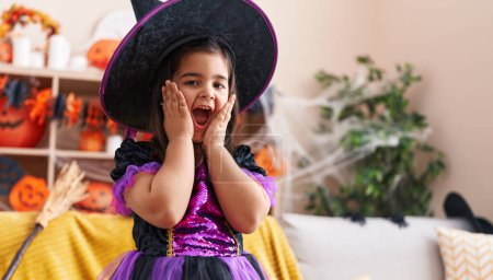 Foto de Adorable chica hispana teniendo fiesta de halloween con expresión sorpresa en casa - Imagen libre de derechos