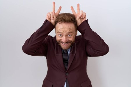Photo for Middle age business man with beard wearing suit and tie posing funny and crazy with fingers on head as bunny ears, smiling cheerful - Royalty Free Image