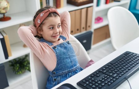 Photo for Adorable hispanic girl student using computer relaxed with hands on head at classroom - Royalty Free Image