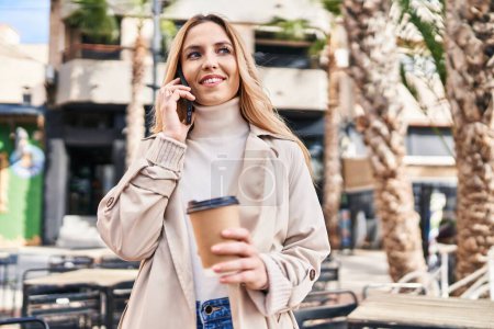 Photo for Young blonde woman talking on smartphone drinking coffee at coffee shop terrace - Royalty Free Image