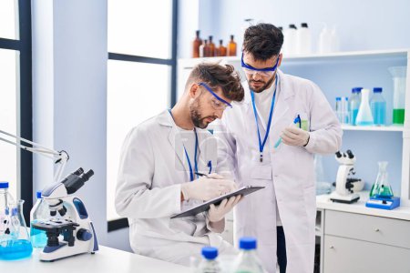Téléchargez les photos : Young couple wearing scientist uniform working at laboratory - en image libre de droit