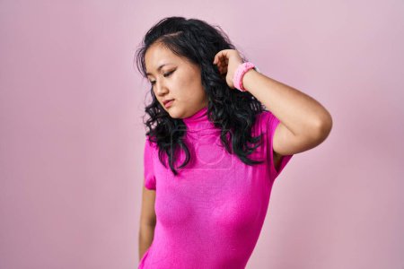 Téléchargez les photos : Jeune femme asiatique debout sur fond rose étirant le dos, fatigué et détendu, somnolent et bâillant tôt le matin - en image libre de droit