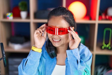 Téléchargez les photos : Jeune femme chinoise streamer jouer à un jeu vidéo en utilisant des lunettes de réalité virtuelle à la salle de jeux - en image libre de droit