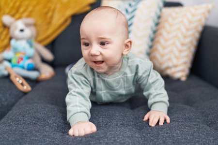 Photo for Adorable caucasian baby crawling on sofa at home - Royalty Free Image