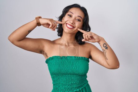 Téléchargez les photos : Jeune femme hispanique debout sur fond isolé souriant gai montrant et pointant avec les doigts dents et la bouche. concept de santé dentaire. - en image libre de droit