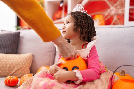 Téléchargez les photos : Africaine américaine fille portant costume de princesse tenant panier de citrouille à la maison - en image libre de droit