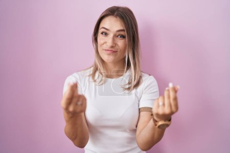 Photo for Blonde caucasian woman standing over pink background doing money gesture with hands, asking for salary payment, millionaire business - Royalty Free Image
